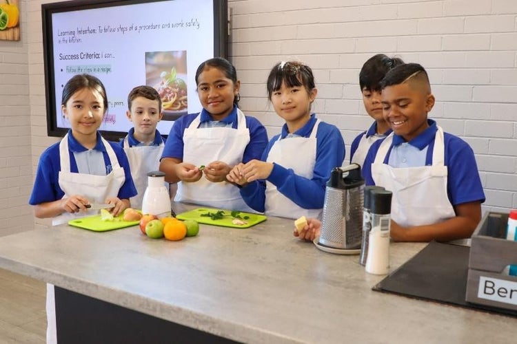 A group of kids in aprons in the paddock to plate kitchen